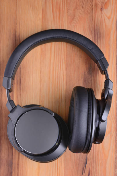 istock Full-size wireless headphones, close-up on wood texture background 1304727404