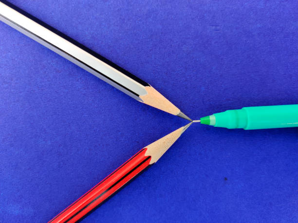 istock Two pencil and pen pointing each other isolated on blue background 1304727664