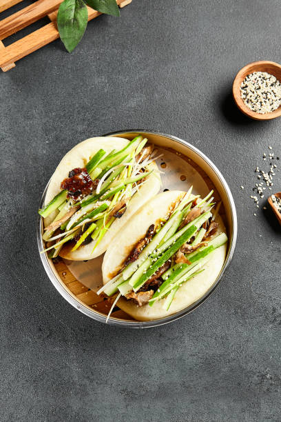 Bao bun with roast duck. Bamboo steamer on dark slate table. Chinese, asian, authentic food concept Bao bun with roast duck. Bamboo steamer on dark slate table. Chinese, asian, authentic food concept. hoisin sauce stock pictures, royalty-free photos & images