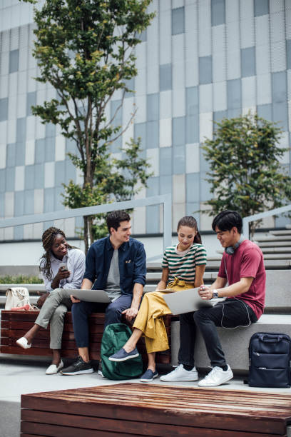 College Students Studying Together Multiethnic group of university students sitting outdoors and studying together on their laptops. teenager adolescence campus group of people stock pictures, royalty-free photos & images