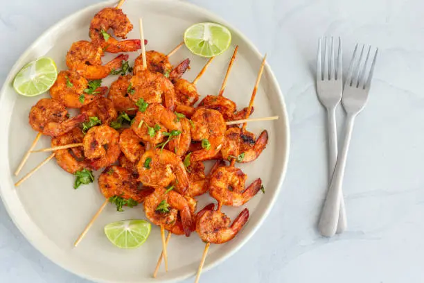Grilled Shrimp Skewers on a Plate with Cilantro and Lemon Top Down Close-Up Photo