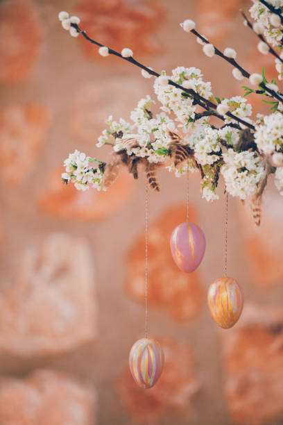 istock Still life with blossom branches and pussy willow decorated with self painted Easter eggs and feathers in front of a rustic stone wall 1304732491