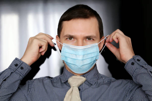 istock Man in office clothes puts on medical face mask 1304734616