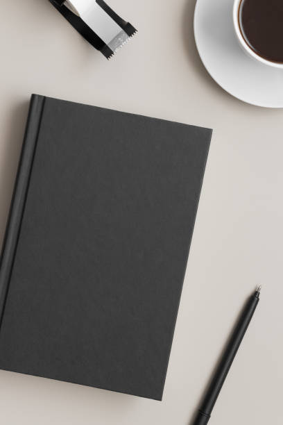 istock Black book mockup with a coffee and workspace accessories on a beige table. 1304736165