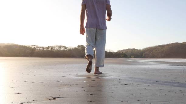 istock POV of man walking down sandy beach at sunrise 1304742859