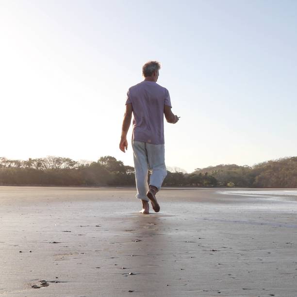 istock POV of man walking down sandy beach at sunrise 1304742870