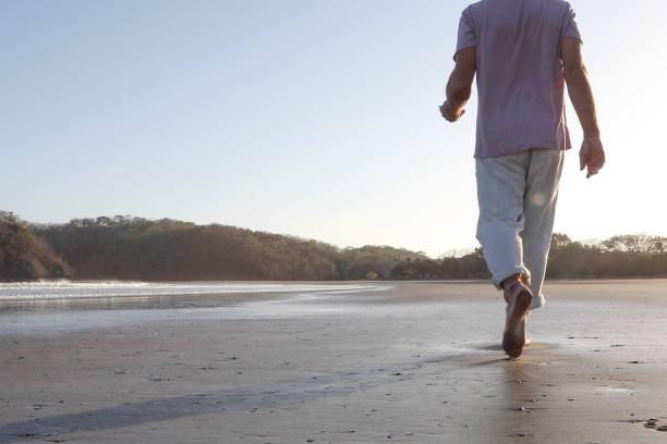 istock POV of man walking down sandy beach at sunrise 1304742875