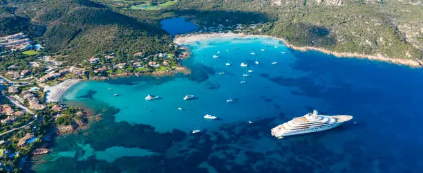 View from above, stunning aerial view of the Grande Pevero beach with boats and luxury yachts sailing on a turquoise, clear water. Sardinia, Italy.