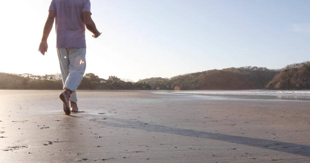 istock POV of man walking down sandy beach at sunrise 1304743047