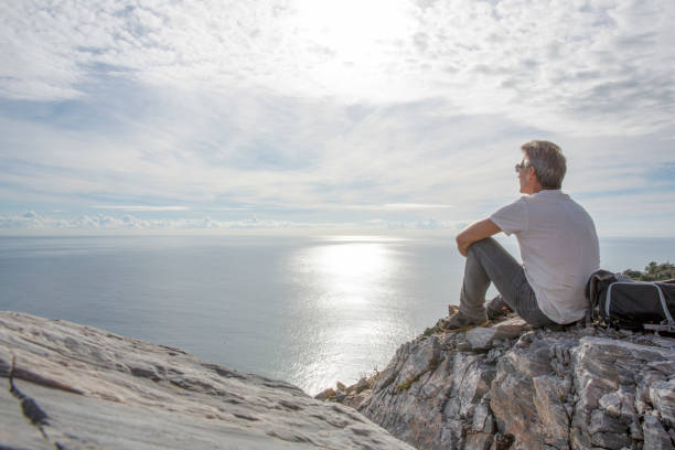 istock Man relaxes on coastal cliff in the morning 1304743072