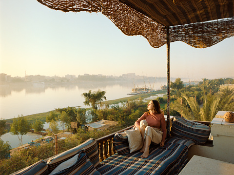 Young woman  sitting on terrace and looking at Nile at sunset in Luxor