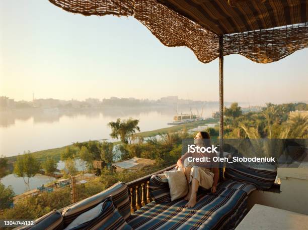 Woman Sitting On Terrace And Looking At Nile At Sunset In Luxor Stock Photo - Download Image Now