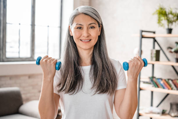 istock Active middle-aged woman exercising with dumbbells at home 1304744723