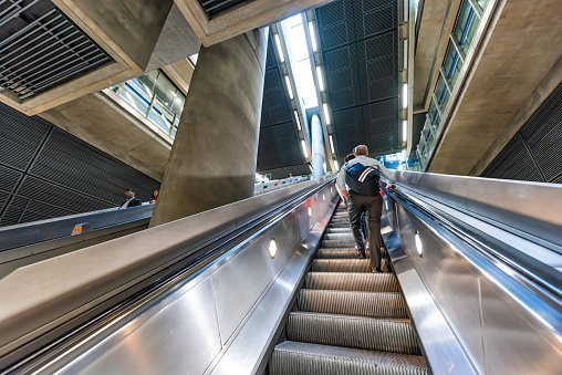 London, UK - June 26, 2018: People commuters riding escalators up inside Underground tube metro during morning commute in Canary Wharf
