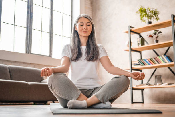 自宅で瞑想する灰色の髪の成熟した白人女性 - yoga zen like women meditating ストックフォトと画像