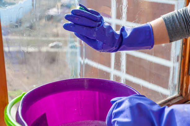istock A woman in protective gloves cleaning the window 1304744788