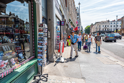 London, UK - June 24, 2018: Gift store shop with people walking on sidewalk street by many souvenirs in summer in United Kingdom