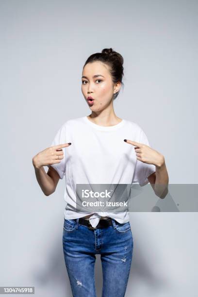 Asian Young Woman Pointing At Tshirt Stock Photo - Download Image Now - T-Shirt, Asian and Indian Ethnicities, One Woman Only