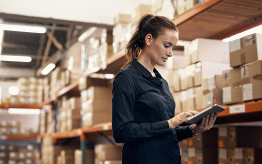 Shot of a young woman using a digital tablet while working in a warehouse