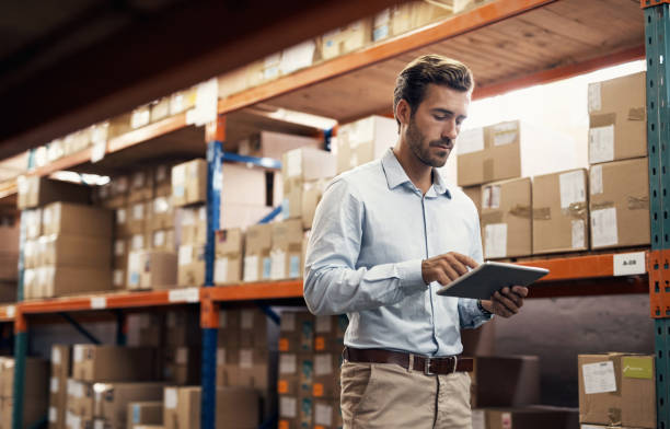 Taking better control with technology Shot of a young man using a digital tablet while working in a warehouse shipping photos stock pictures, royalty-free photos & images