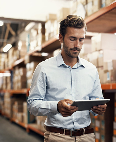 Shot of a young man using a digital tablet while working in a warehouse