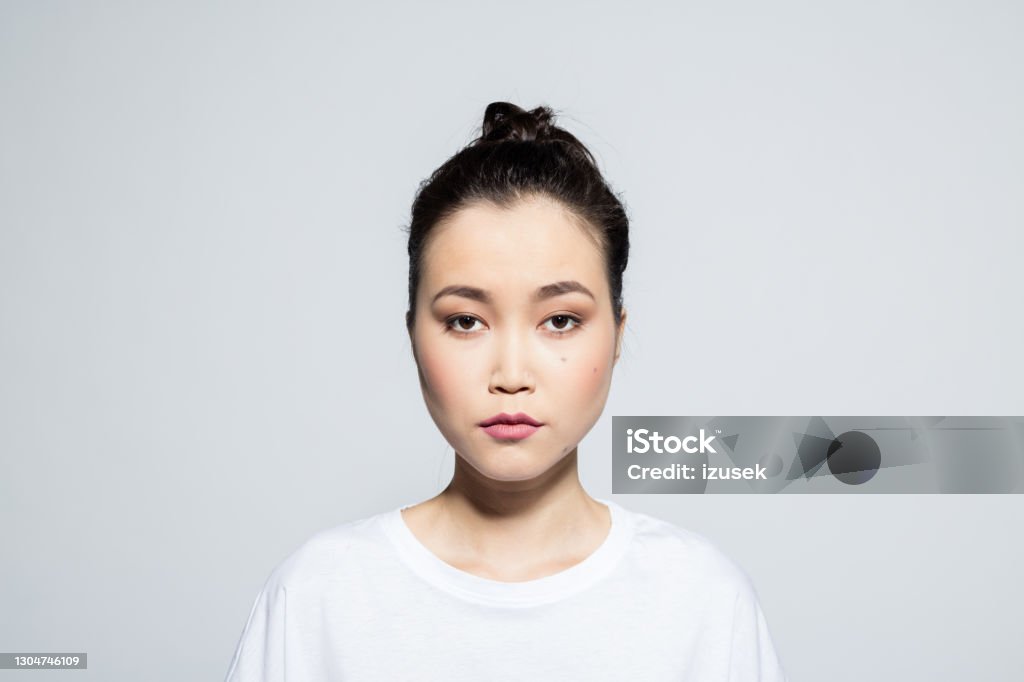 Beautiful asian young woman Portrait of beautiful asian young woman wearing white t-shirt, looking at camera. Studio shot, grey background. 20-24 Years Stock Photo