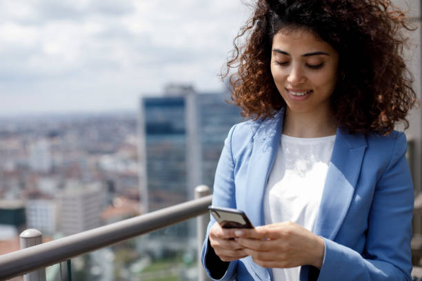 istock Smiling young businesswoman using mobile phone on the rooftop 1304748642