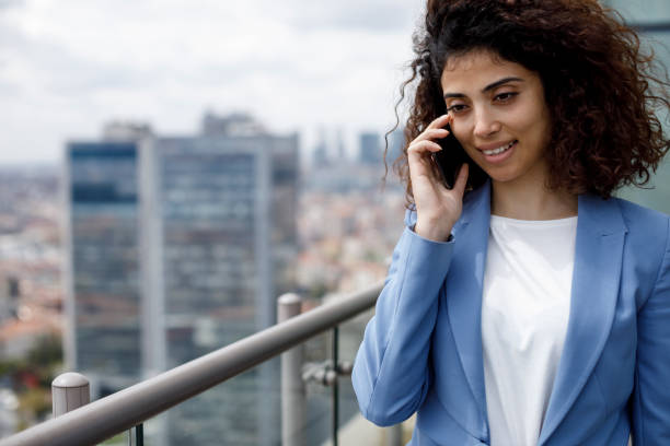 istock Young smiling businesswoman using mobile phone outdoor 1304748661