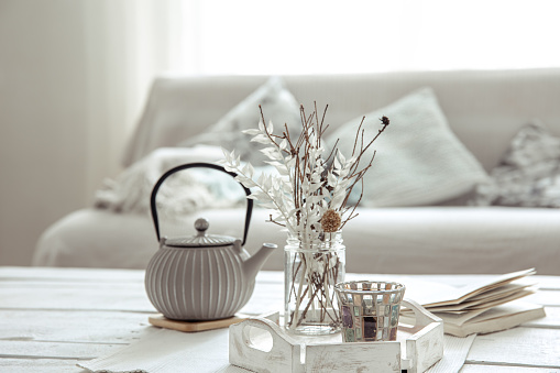 Teapot and decor details on the table in the living room in a hygge style. Home comfort concept.