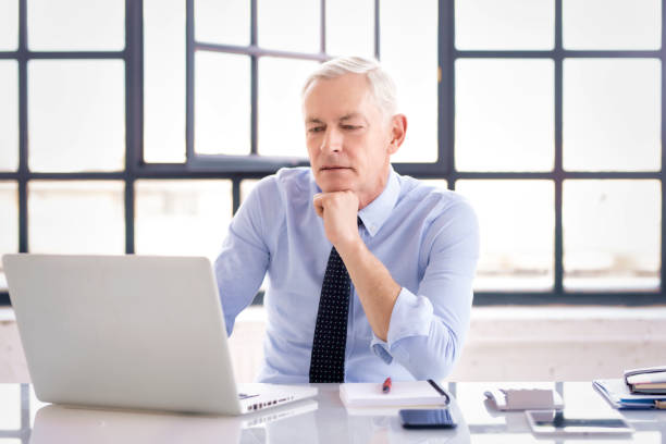 istock Executive senior businessman working on his laptop while sitting at desk at the office 1304751480