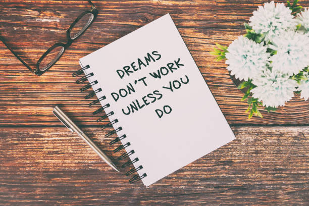 istock Inspirational Quotes text on notepad - Dreams don't work unless you do. 1304753440