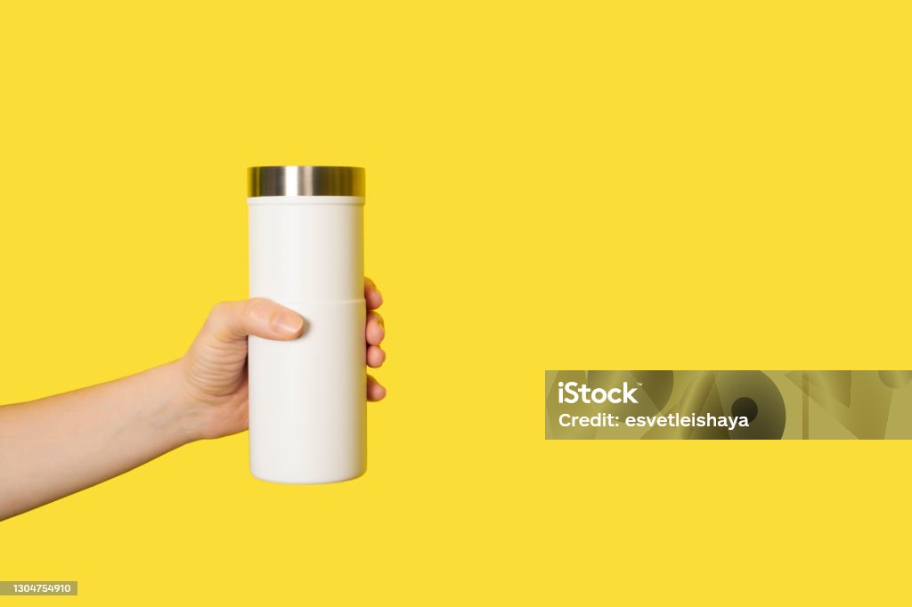 Hand holds white travel mug isolated on white background. Thermo cup or tumbler in female hand. Banner with copy space Hand holds white travel mug isolated on white background. Thermo cup or tumbler in female hand. Banner with copy space. Cup Stock Photo