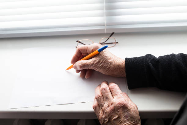 vieilles mains écrivant sur le morceau de papier. les mains d’une femme âgée écrivent - writing chair photos et images de collection
