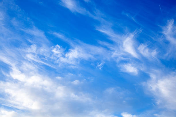 istock blue sky with clouds from below, high flying passenger plane with condensation trail. jet plane flying overhead diagonally in sky with sunlight. 1304758917