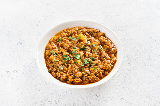Keema curry in bowl over light stone background with copy space. Indian and pakistani style dish. Close up view