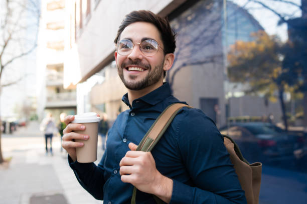 istock Young man holding a cup of coffee while walking outdoors. 1304762188