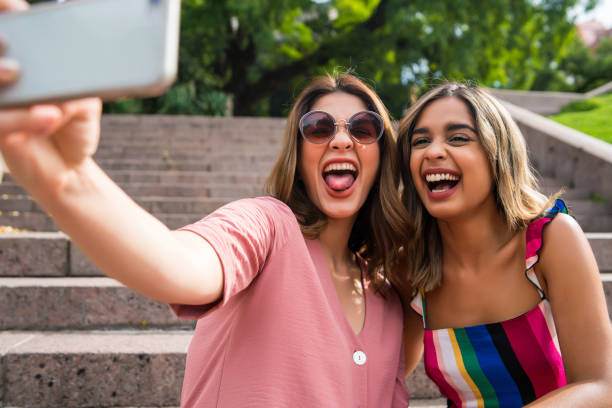 istock Two friends taking selfie with phone outdoors. 1304762232