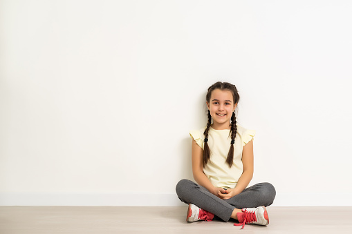 lovely little girl sitting on the floor, isolated on white background.