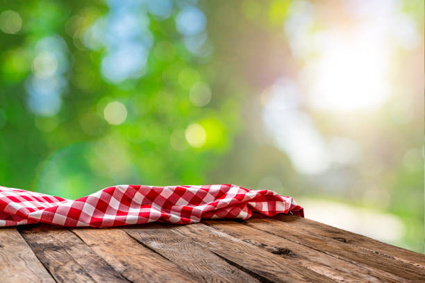 istock Empty rustic picnic table with crumpled gingham cloth against defocused nature background 1304763846