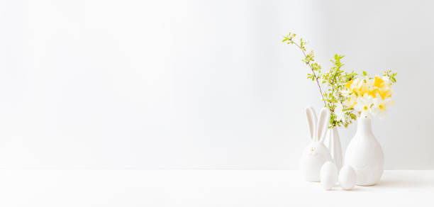 istock Home interior with easter decor. Daffodils in a vase, spring flowers on a light background 1304765066