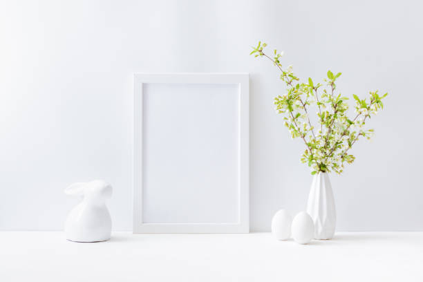 istock Home interior with easter decor. Mockup with a white frame and spring flowers in a vase on a light background 1304765080