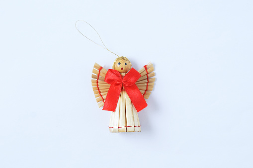 Christmas decoration straw angel with a red bow on a white background.