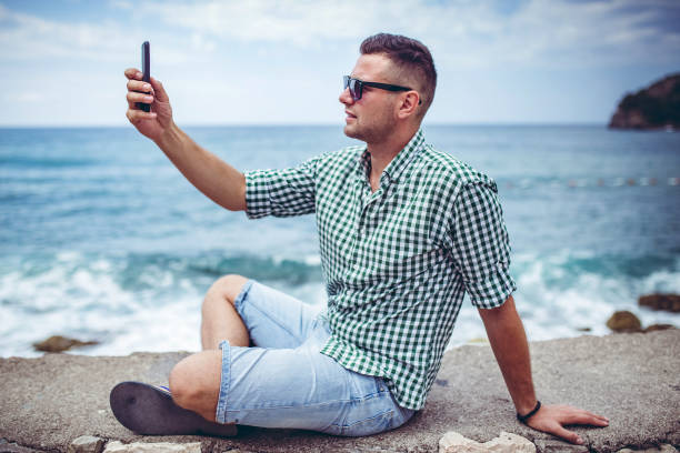 istock Man relaxing on beach in Budva Montenegro and making selfie 1304770919