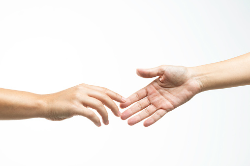 Two hands are almost touching for handshake on white background.
