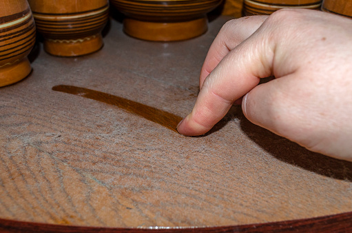 A woman holds her finger along a thick layer of dust on a wooden shelf. Allergen in the apartment