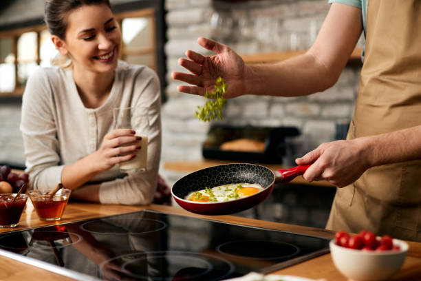 Close-up of man frying eggs with vegetables for breakfast.