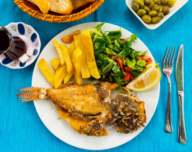 Portion of fried lionfish served with french fries, lemon and greens, typical dish of Turke
