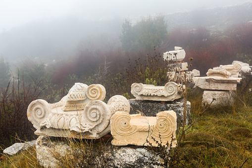 View of ancient sculptures fragments, reliefs and architectural elements outdoors on foggy winter day on archaeological site of Sagalassos in Turkey