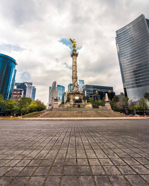 Angular taker of the Angel of Independence and Paseo de la Reforma during the day in Mexico City Photograph with wide-angle lens taken during the day at the Angel of Independence in Paseo de la Reforma, Mexico City. mexico street scene stock pictures, royalty-free photos & images