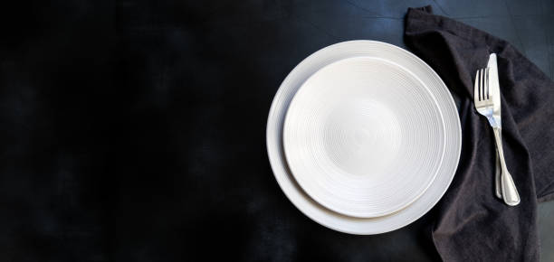 istock White craft plate, cutlery and napkin on dark stone table 1304779078